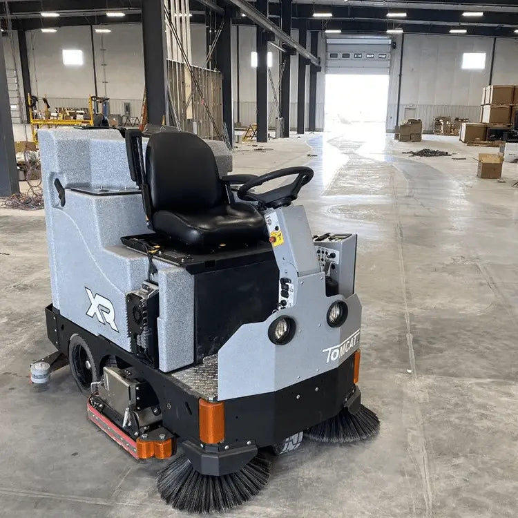 Rider floor scrubber with black seat, side controls, and front sweeping brush
