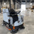 Rider floor scrubber with black seat, side controls, and front sweeping brush